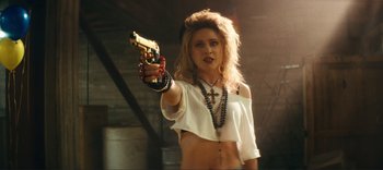 Movie still from “Weird: The Al Yankovic Story” (2022), directed by Eric Appel – A woman holding a gun in her hand; Close Up shot, Over the shoulder angle