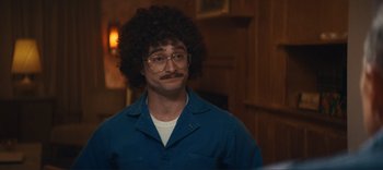 Movie still from “Weird: The Al Yankovic Story” (2022), directed by Eric Appel – A man in a blue shirt with a mustache and curly hair; Close Up shot, Over the shoulder angle