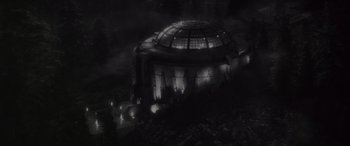 Movie still from “Werewolf by Night” (2022), directed by Michael Giacchino – A black - and - white photo of a building at night; Extreme Wide shot, High angle