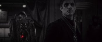 Movie still from “Werewolf by Night” (2022), directed by Michael Giacchino – A man in a dark room looking at the camera; Close Up shot, Over the shoulder angle