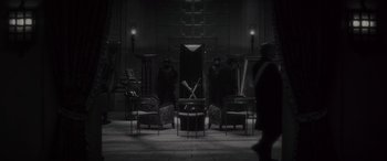 Movie still from “Werewolf by Night” (2022), directed by Michael Giacchino – A group of people standing around a living room; Wide shot, High angle