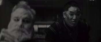 Movie still from “Werewolf by Night” (2022), directed by Michael Giacchino – A man in a black jacket is looking to his left; Close Up shot, Over the shoulder angle