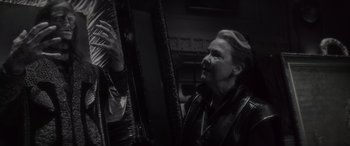 Movie still from “Werewolf by Night” (2022), directed by Michael Giacchino – An older woman is looking at a piece of art; Close Up shot, Over the shoulder angle