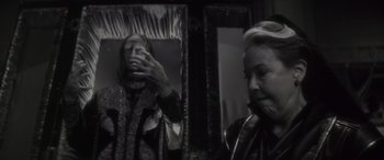 Movie still from “Werewolf by Night” (2022), directed by Michael Giacchino – A black and white photo of a woman looking at herself in the mirror; Close Up shot, Over the shoulder angle