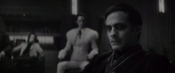 Movie still from “Werewolf by Night” (2022), directed by Michael Giacchino – A man sitting in front of another man in a chair; Medium shot, Over the shoulder angle