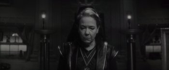 Movie still from “Werewolf by Night” (2022), directed by Michael Giacchino – An older woman wearing a black outfit with a hood over her head; Close Up shot, High angle