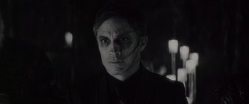 Movie still from “Werewolf by Night” (2022), directed by Michael Giacchino – A black and white photo of a man with a creepy face; Close Up shot, Over the shoulder angle