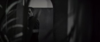 Movie still from “Werewolf by Night” (2022), directed by Michael Giacchino – A black and white photo of a man standing in front of a wall; Close Up shot, Low angle