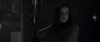 Movie still from “Werewolf by Night” (2022), directed by Michael Giacchino – A woman holding a sword in a dark room; Close Up shot, Over the shoulder angle