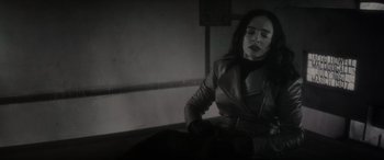 Movie still from “Werewolf by Night” (2022), directed by Michael Giacchino – A black and white photo of a woman in a leather jacket; Medium shot, High angle