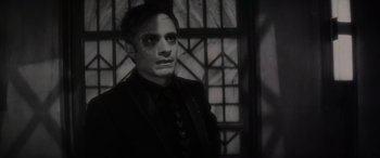 Movie still from “Werewolf by Night” (2022), directed by Michael Giacchino – A man in a black suit with a black mask on his face; Close Up shot, High angle