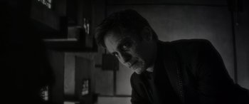 Movie still from “Werewolf by Night” (2022), directed by Michael Giacchino – A black and white photo of a man in a dark room; Close Up shot, Low angle