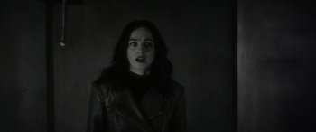 Movie still from “Werewolf by Night” (2022), directed by Michael Giacchino – A woman in a leather jacket is standing in a dark room; Close Up shot, Low angle