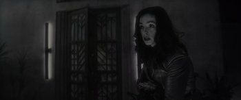 Movie still from “Werewolf by Night” (2022), directed by Michael Giacchino – A woman in a leather jacket standing next to a door; Close Up shot, Low angle