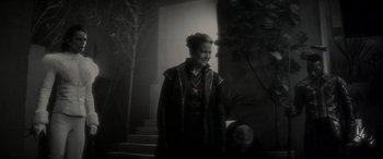 Movie still from “Werewolf by Night” (2022), directed by Michael Giacchino – A woman standing on steps in front of a building; Medium shot, Over the shoulder angle