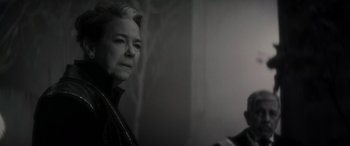 Movie still from “Werewolf by Night” (2022), directed by Michael Giacchino – An older woman looking at the camera in a black and white photo; Close Up shot, Over the shoulder angle