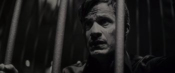 Movie still from “Werewolf by Night” (2022), directed by Michael Giacchino – A black and white photo of a man behind bars; Close Up shot, High angle
