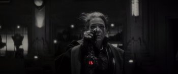 Movie still from “Werewolf by Night” (2022), directed by Michael Giacchino – A woman with a red light in her hand; Close Up shot, Over the shoulder angle