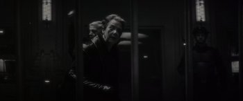 Movie still from “Werewolf by Night” (2022), directed by Michael Giacchino – A man standing in front of a window; Medium shot, Over the shoulder angle