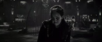 Movie still from “Werewolf by Night” (2022), directed by Michael Giacchino – An old woman is looking at the camera in a dark room; Close Up shot, Low angle