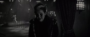 Movie still from “Werewolf by Night” (2022), directed by Michael Giacchino – A person with a face paint on a dark room; Close Up shot, Over the shoulder angle