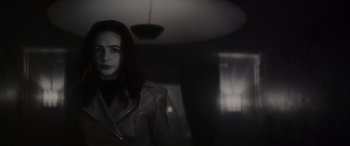 Movie still from “Werewolf by Night” (2022), directed by Michael Giacchino – A woman in a leather jacket standing next to a window; Medium shot, Over the shoulder angle