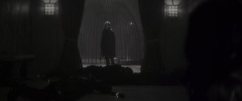 Movie still from “Werewolf by Night” (2022), directed by Michael Giacchino – A woman standing in a dark room next to a dead body; Wide shot, Low angle