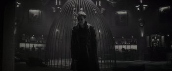 Movie still from “Werewolf by Night” (2022), directed by Michael Giacchino – A woman standing in front of an iron cage; Medium shot, Low angle