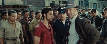 Movie still from “West Side Story” (2021), directed by Steven Spielberg – A group of men standing next to each other in front of a fence; Medium shot, Over the shoulder angle