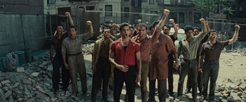 Movie still from “West Side Story” (2021), directed by Steven Spielberg – A group of men standing next to each other on a street; Wide shot, Low angle