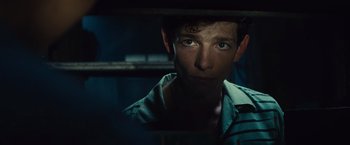 Movie still from “West Side Story” (2021), directed by Steven Spielberg – A young man is looking at the camera through a window; Close Up shot, Over the shoulder angle