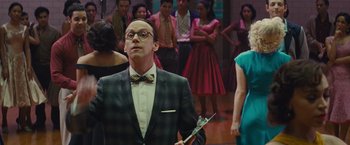 Movie still from “West Side Story” (2021), directed by Steven Spielberg – A man in a suit and bow tie holding a microphone; Medium shot, Over the shoulder angle