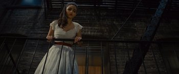 Movie still from “West Side Story” (2021), directed by Steven Spielberg – A woman in a white dress standing next to a railing; Medium shot, Low angle
