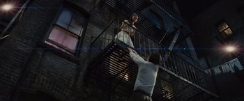 Movie still from “West Side Story” (2021), directed by Steven Spielberg – A man and a woman are standing on a fire escape; Wide shot, Low angle