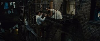 Movie still from “West Side Story” (2021), directed by Steven Spielberg – A man and a woman on a fire escape; Wide shot, Overhead angle