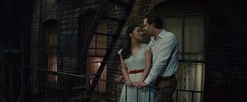 Movie still from “West Side Story” (2021), directed by Steven Spielberg – A man and a woman standing next to each other on stairs; Medium shot, Low angle