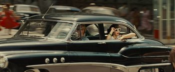 Movie still from “West Side Story” (2021), directed by Steven Spielberg – A man and a woman driving in a vintage car; Wide shot, Over the shoulder angle