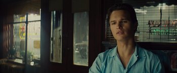 Movie still from “West Side Story” (2021), directed by Steven Spielberg – A man in a blue shirt is sitting in front of a window; Close Up shot, Over the shoulder angle