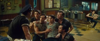 Movie still from “West Side Story” (2021), directed by Steven Spielberg – A group of young men sitting next to each other in a room; Medium shot, Over the shoulder angle