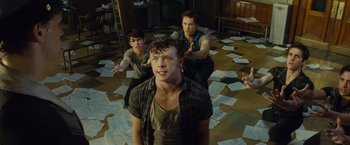 Movie still from “West Side Story” (2021), directed by Steven Spielberg – A group of young men standing on top of papers; Medium shot, High angle