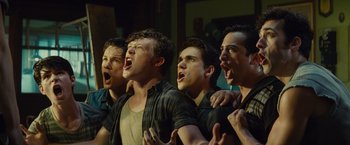 Movie still from “West Side Story” (2021), directed by Steven Spielberg – A group of young men standing next to each other with their mouths open; Medium shot, Low angle