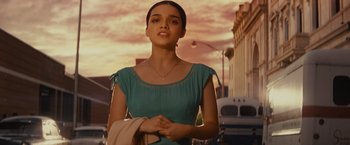 Movie still from “West Side Story” (2021), directed by Steven Spielberg – A woman in a blue dress is standing in the street; Medium shot, Low angle