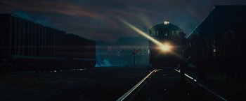 Movie still from “West Side Story” (2021), directed by Steven Spielberg – A train traveling down train tracks at night time; Extreme Wide shot, Low angle