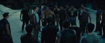 Movie still from “West Side Story” (2021), directed by Steven Spielberg – A group of men standing around each other in the dark; Wide shot, High angle