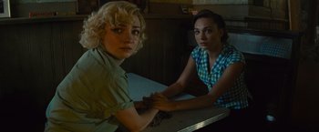 Movie still from “West Side Story” (2021), directed by Steven Spielberg – Two young women sitting at a table holding hands; Close Up shot, Over the shoulder angle