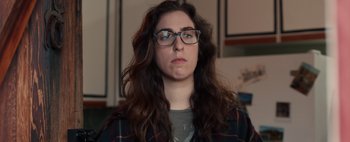 Movie still from “What She Said” (2021), directed by Amy Northup – A woman wearing glasses and a plaid jacket; Close Up shot, Low angle