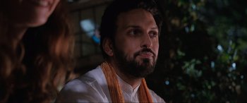 Movie still from “What's Love Got to Do with It?” (2022), directed by Shekhar Kapur – A man with long hair and a beard wearing an orange scarf; Close Up shot, Low angle
