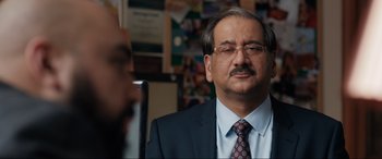 Movie still from “What's Love Got to Do with It?” (2022), directed by Shekhar Kapur – A man in a suit and tie looking at the camera; Close Up shot, Over the shoulder angle