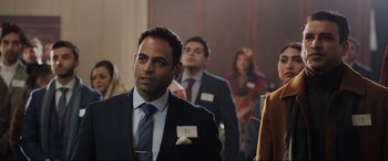 Movie still from “What's Love Got to Do with It?” (2022), directed by Shekhar Kapur – A group of people in suits and ties; Medium shot, Over the shoulder angle