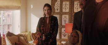 Movie still from “What's Love Got to Do with It?” (2022), directed by Shekhar Kapur – A woman holding a camera in front of a wall with pictures; Medium shot, Over the shoulder angle